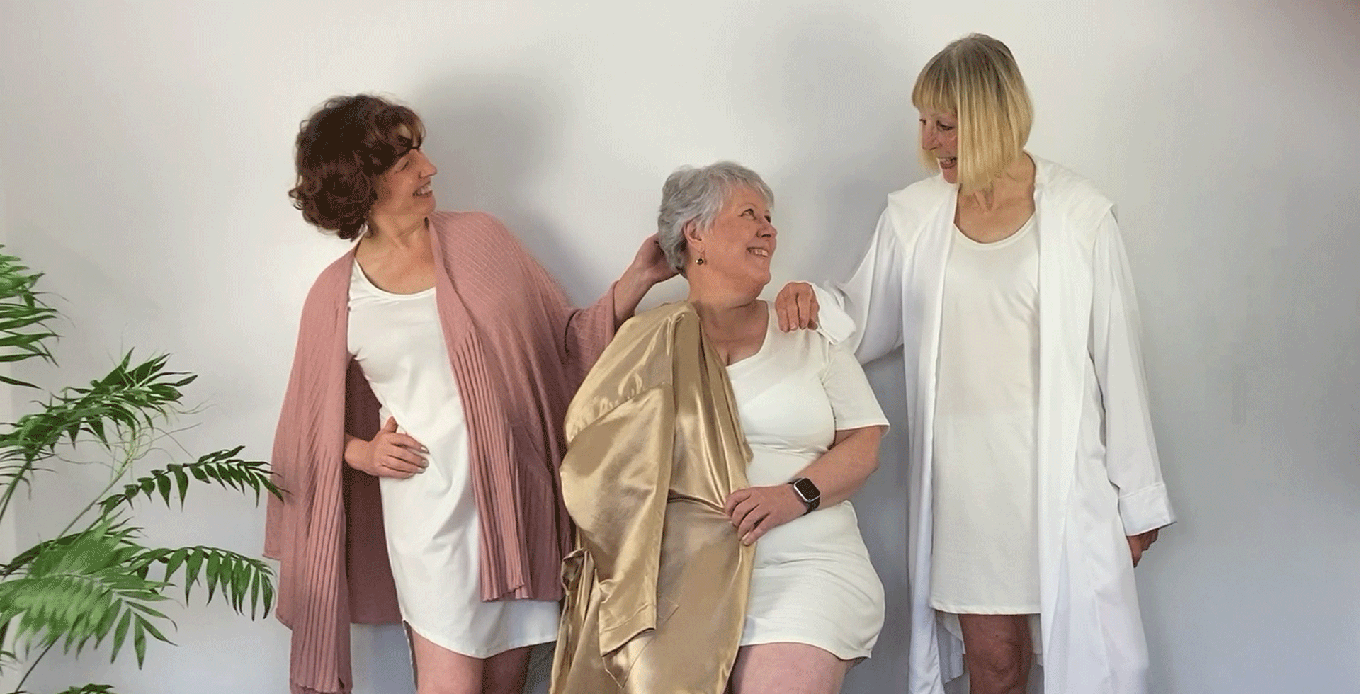 Three gorgeous women all wearing the organic cotton/bamboo mix tee-nightie with model on the left wearing a merino wool knit 'cardi-cape', centre; hemp satin full length wrap and right; bamboo silk hoody, knee-length wrap.