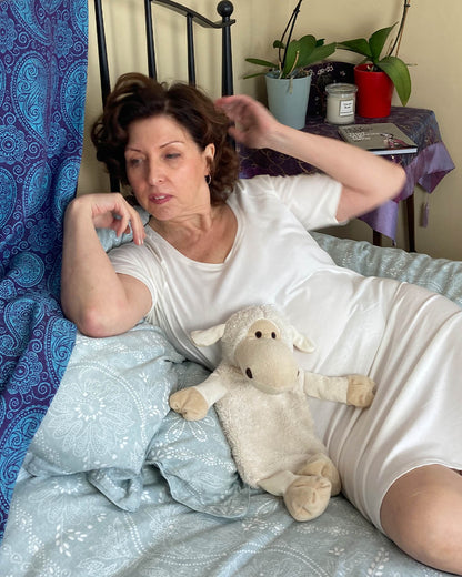 Model lounging on bed wearing the tee-nightie with raglan sleeve. Older ladies nightwear and ethically made fashion